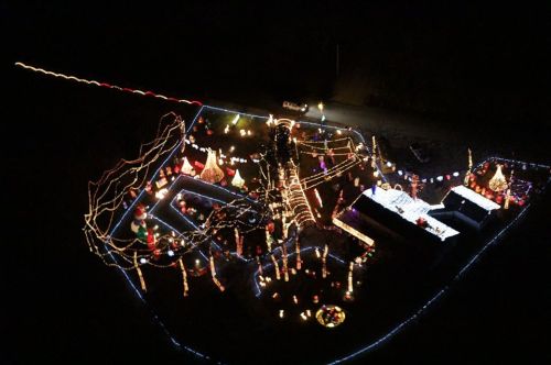 Aerial view of a festive display with colorful lights and decorations illuminating a dark landscape.