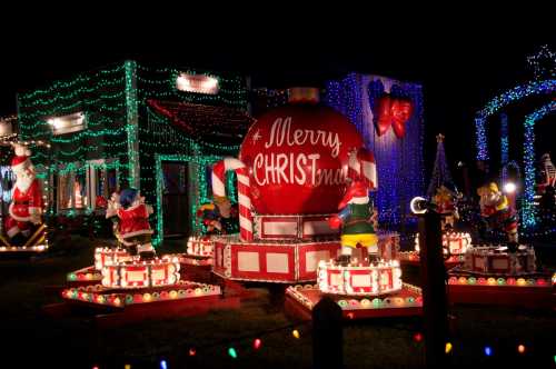 Colorful Christmas display featuring illuminated decorations, Santa figures, and a large "Merry Christmas" ornament.