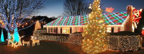 A brightly lit house decorated with colorful Christmas lights, featuring a tree and festive decorations in the yard.