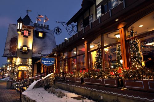 A cozy restaurant with festive decorations and lights, set against a snowy evening backdrop.