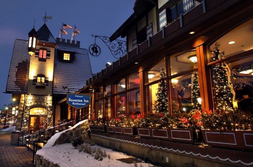A cozy restaurant with festive decorations and lights, set in a charming building during twilight. Snow on the ground.