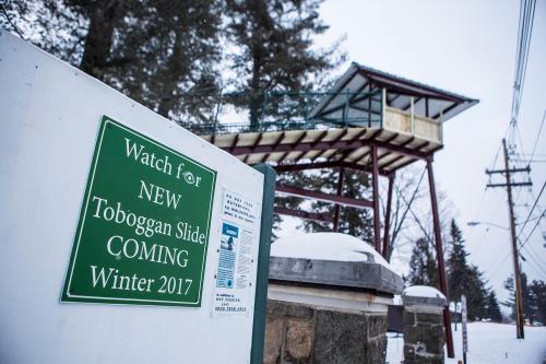 Sign announcing a new toboggan slide coming in Winter 2017, with a snowy landscape and a slide structure in the background.