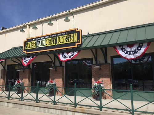 Exterior of EnterTRAINment Junction, featuring a large sign and patriotic bunting on a sunny day.