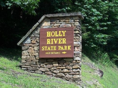 Sign for Holly River State Park, featuring stone structure and yellow lettering, indicating the main entrance.