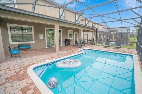 A backyard with a pool, patio furniture, and a screened enclosure under a clear blue sky.
