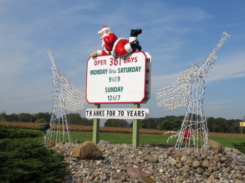 A festive sign featuring Santa, with holiday lights and a message celebrating 70 years of service.