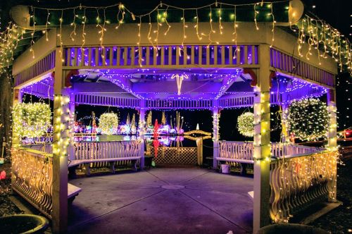 A beautifully lit gazebo adorned with colorful lights, surrounded by festive decorations and a vibrant holiday display.