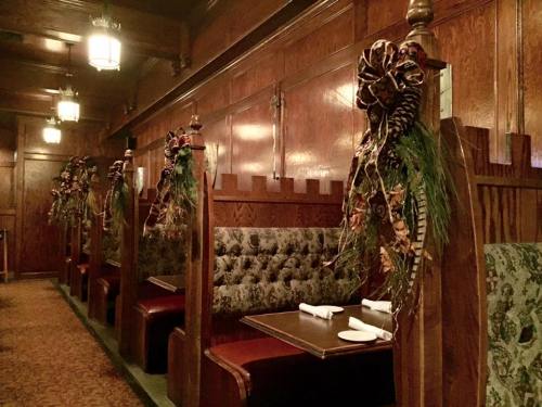Cozy restaurant interior with wooden booths, festive decorations, and elegant lighting.