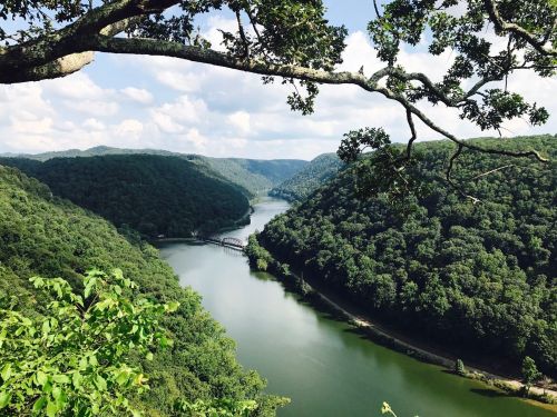 A scenic view of a river winding through lush green hills under a partly cloudy sky.