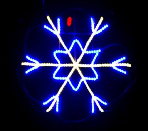 A glowing blue and white snowflake design with pointed tips, set against a dark background.