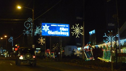 A nighttime scene featuring festive lights and a sign for Ober Gatlinburg, with a vehicle in the foreground.
