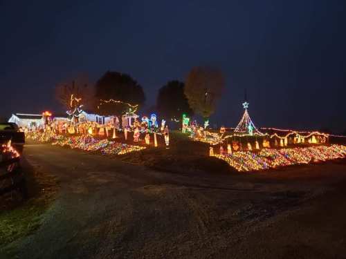 A festive display of colorful holiday lights adorning houses and decorations in a dark evening setting.