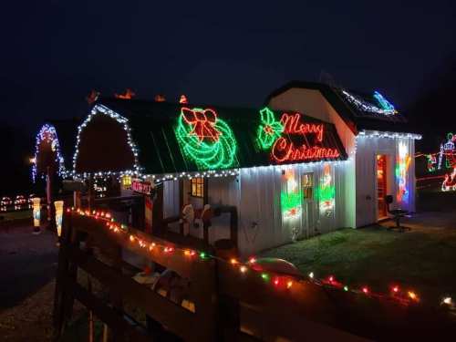 A festive display of Christmas lights on a small building, featuring colorful decorations and a "Merry Christmas" sign.