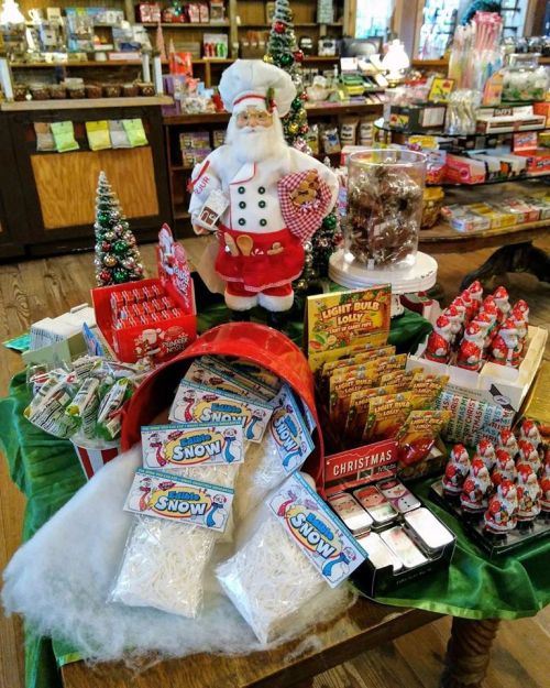 A festive display featuring a Santa figure, candy, and holiday decorations in a cozy shop setting.