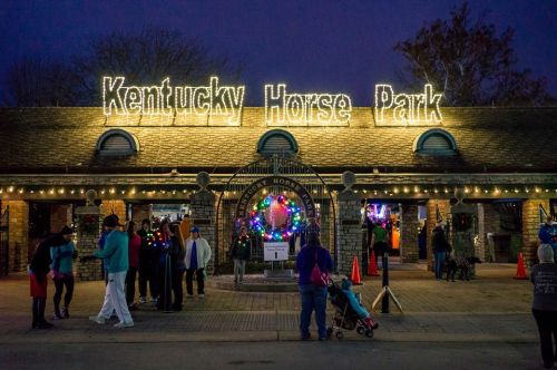 Entrance to Kentucky Horse Park, adorned with festive lights and decorations, bustling with visitors at dusk.