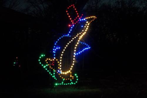 A colorful light display of a penguin wearing a top hat and skating, set against a dark background.