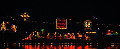 Colorful Christmas lights display featuring a nativity scene, stars, and the text "For God So Loved the World."