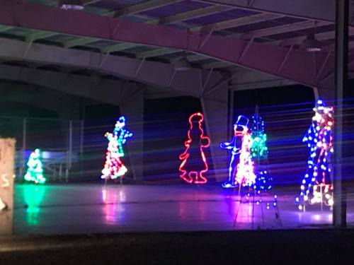 Colorful holiday lights depicting various figures in a festive display under a covered area at night.