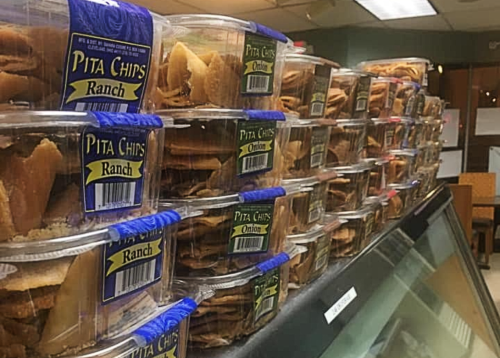 A display of stacked containers filled with various flavors of pita chips, labeled "Ranch" and "Onion."