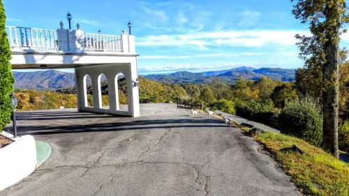 A scenic view of mountains under a clear blue sky, with a white structure and winding road in the foreground.