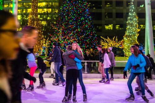 A lively ice skating rink decorated with colorful Christmas lights, featuring skaters enjoying the festive atmosphere.