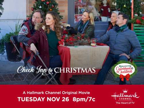 A group of four people sits around a festive table, promoting the Hallmark movie "Check Inn to Christmas."