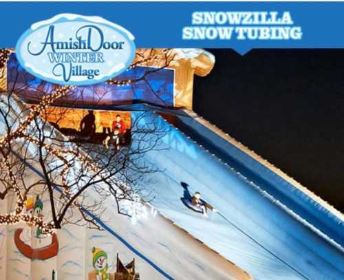 A snowy tubing hill at night with people sliding down, featuring festive decorations and a sign for Snowzilla at Amish Door Village.