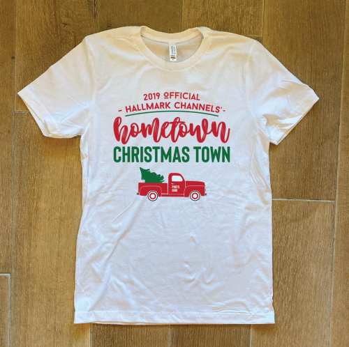 White t-shirt featuring "2019 Official Hallmark Channel's Hometown Christmas Town" with a vintage truck graphic.