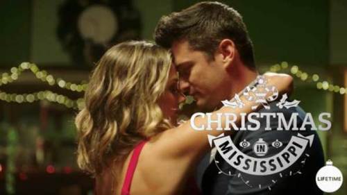 A couple shares a romantic moment, embracing closely, with festive decorations in the background. Text overlay: "Christmas in Mississippi."