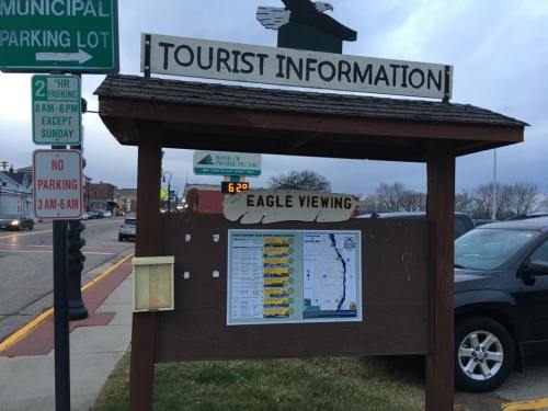 Sign for tourist information featuring a map for eagle viewing, with a parking sign in the background.