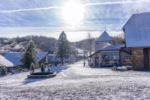 A snowy landscape with trees and buildings under a bright sun, creating a serene winter scene.