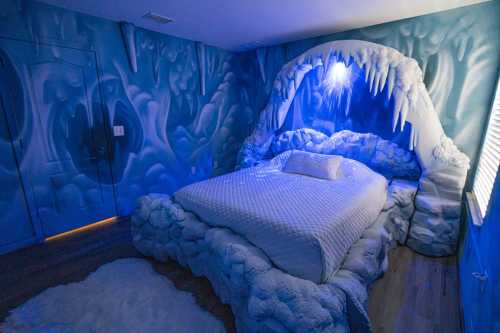 A whimsical bedroom with icy blue walls, a cave-like bed, and cloud-shaped decor, creating a frosty atmosphere.