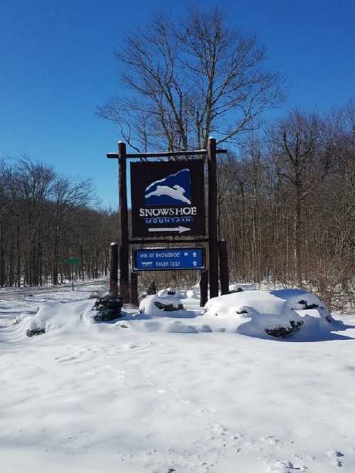 Sign for Snowshoe Mountain, surrounded by snow, with directions to Inn at Snowshoe and Raven Golf.