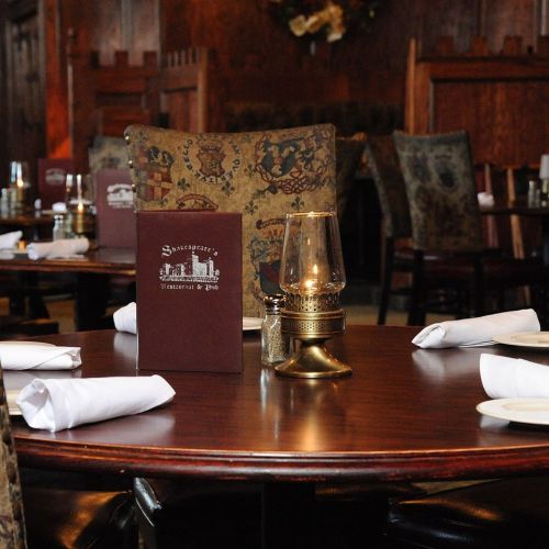 A cozy restaurant interior with wooden decor, tables set with white napkins, and a candle centerpiece.