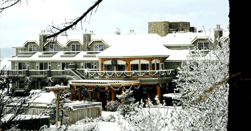 A snow-covered hotel with festive decorations, surrounded by trees and a winter landscape.