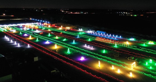 Aerial view of a colorful light display with vibrant patterns and shapes in a dark landscape.