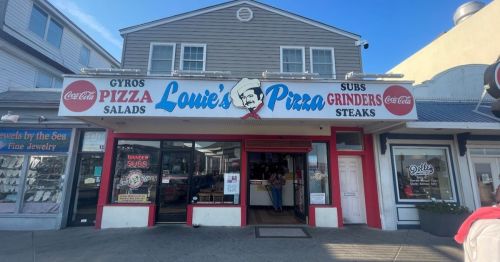 A storefront with a sign reading "Louie's Pizza" featuring pizza, gyros, subs, and salads, under a clear blue sky.