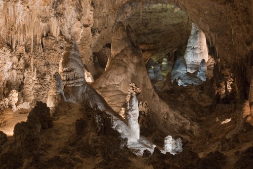 A stunning cave interior featuring stalagmites and stalactites, illuminated by soft lighting, creating a mystical atmosphere.