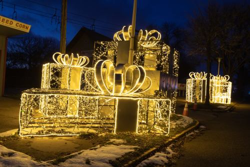 Brightly lit gift boxes adorned with bows, glowing against a dark evening sky.