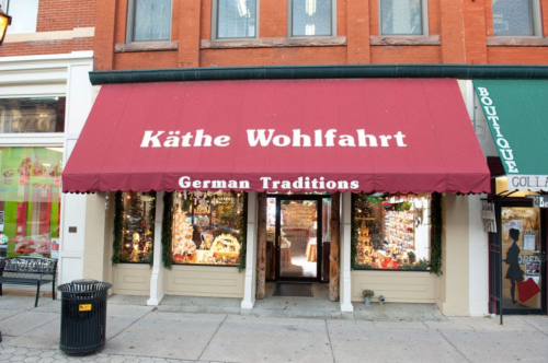 Storefront of Käthe Wohlfahrt featuring a red awning and displays of German holiday decorations.