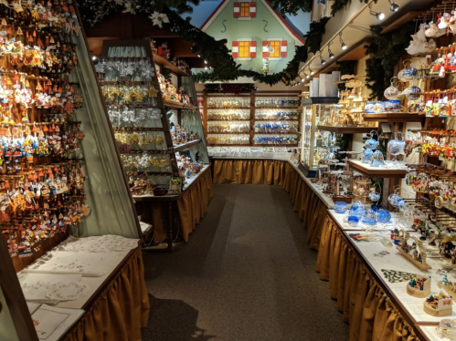 A festive shop interior filled with colorful ornaments and glassware, displayed on shelves and tables.