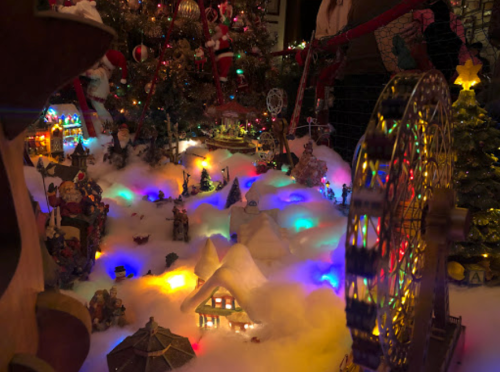 A festive miniature scene with colorful lights, snow, and decorations, featuring a ferris wheel and small buildings.