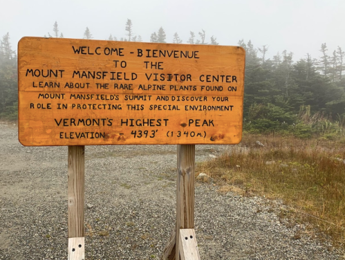 Wooden sign at Mount Mansfield Visitor Center, welcoming visitors and highlighting Vermont's highest peak and its alpine plants.