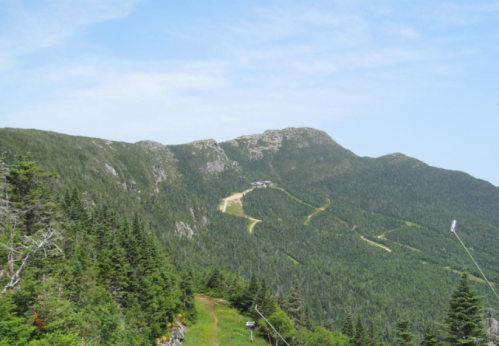 A scenic view of a mountain landscape with lush greenery and a clear blue sky.