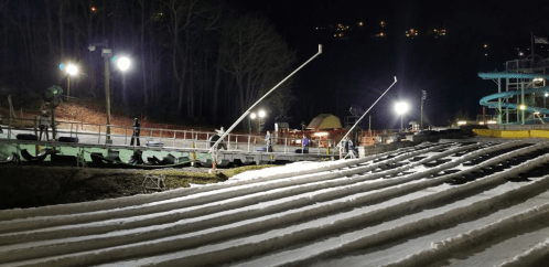 Nighttime view of a snow-covered slope with lights and equipment, ready for winter activities.