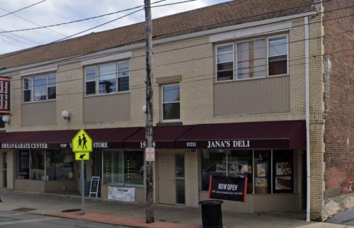 A two-story building with storefronts, including "Jana's Deli," located on a street with a pedestrian crossing sign.