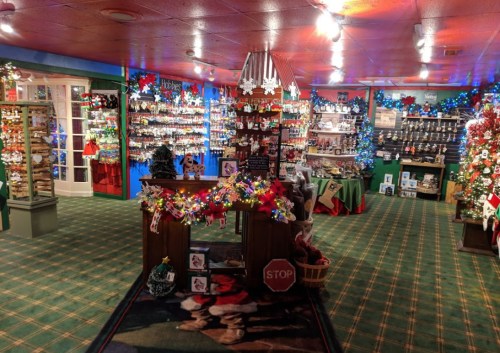 A festive shop interior decorated with Christmas lights, ornaments, and holiday displays, featuring a welcoming counter.