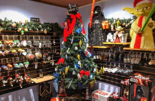 A decorated Christmas tree surrounded by Star Wars merchandise, including ornaments and figures of characters like Yoda and Darth Vader.