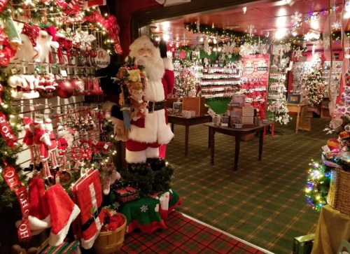 A festive shop filled with Christmas decorations, ornaments, and a life-sized Santa figure welcoming visitors.