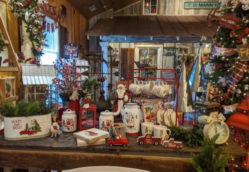 A festive display of holiday decorations, including Santa figurines, red trucks, and various Christmas-themed items.